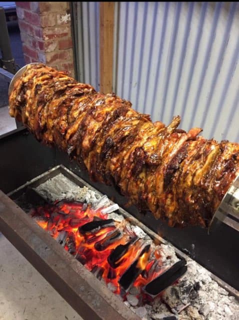 Meat rotating on spit over hot coals